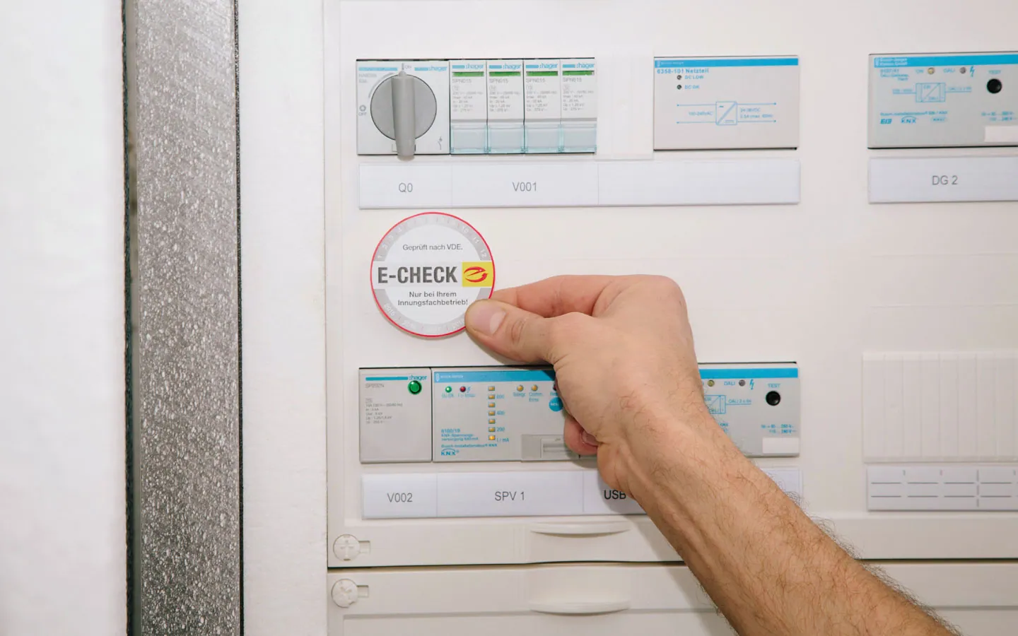 E-CHECK - Mitarbeiter klebt in der Verteilung die E-CHECK Plakette an &middot; Elektro Roth